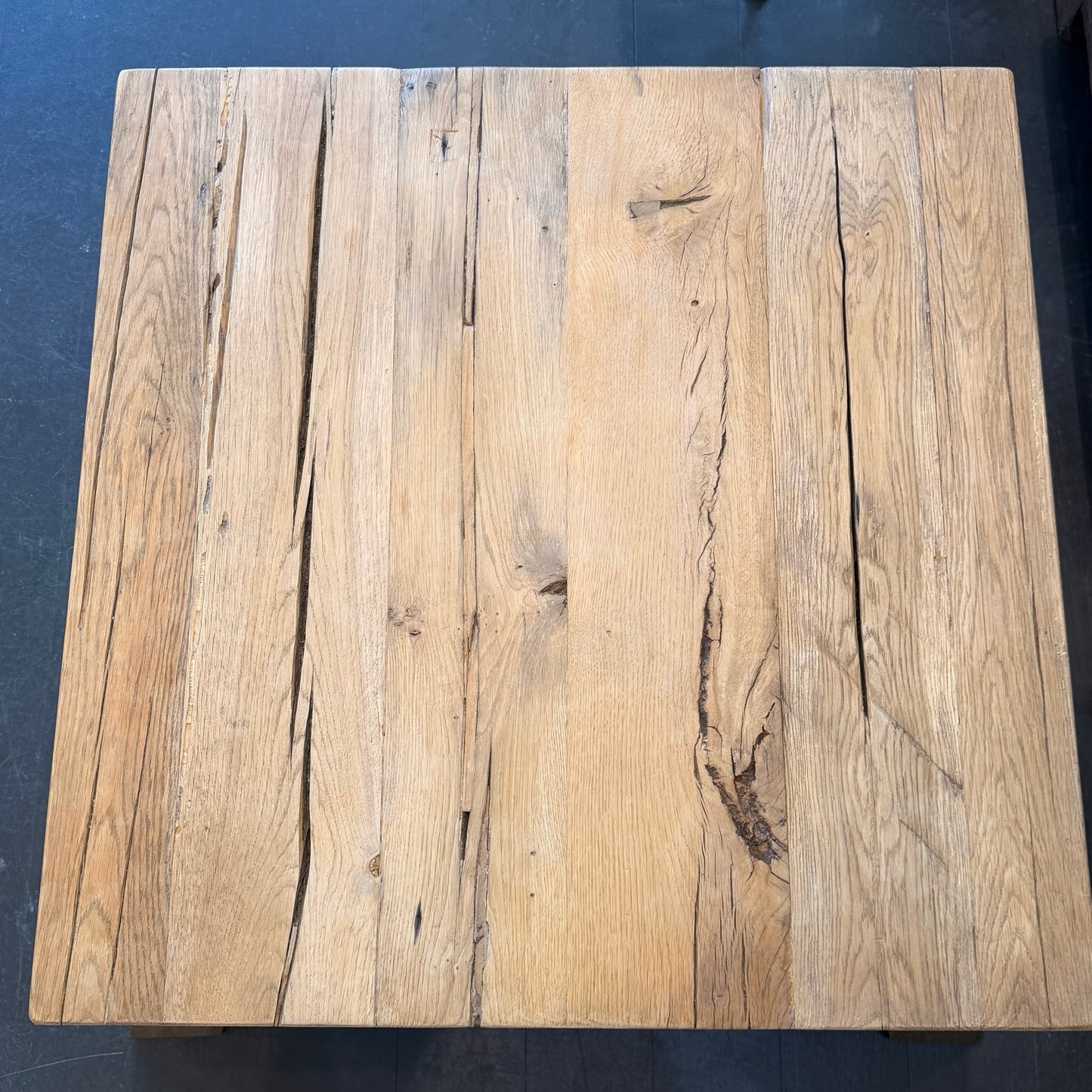 Square wooden table with a rustic finish on a dark background