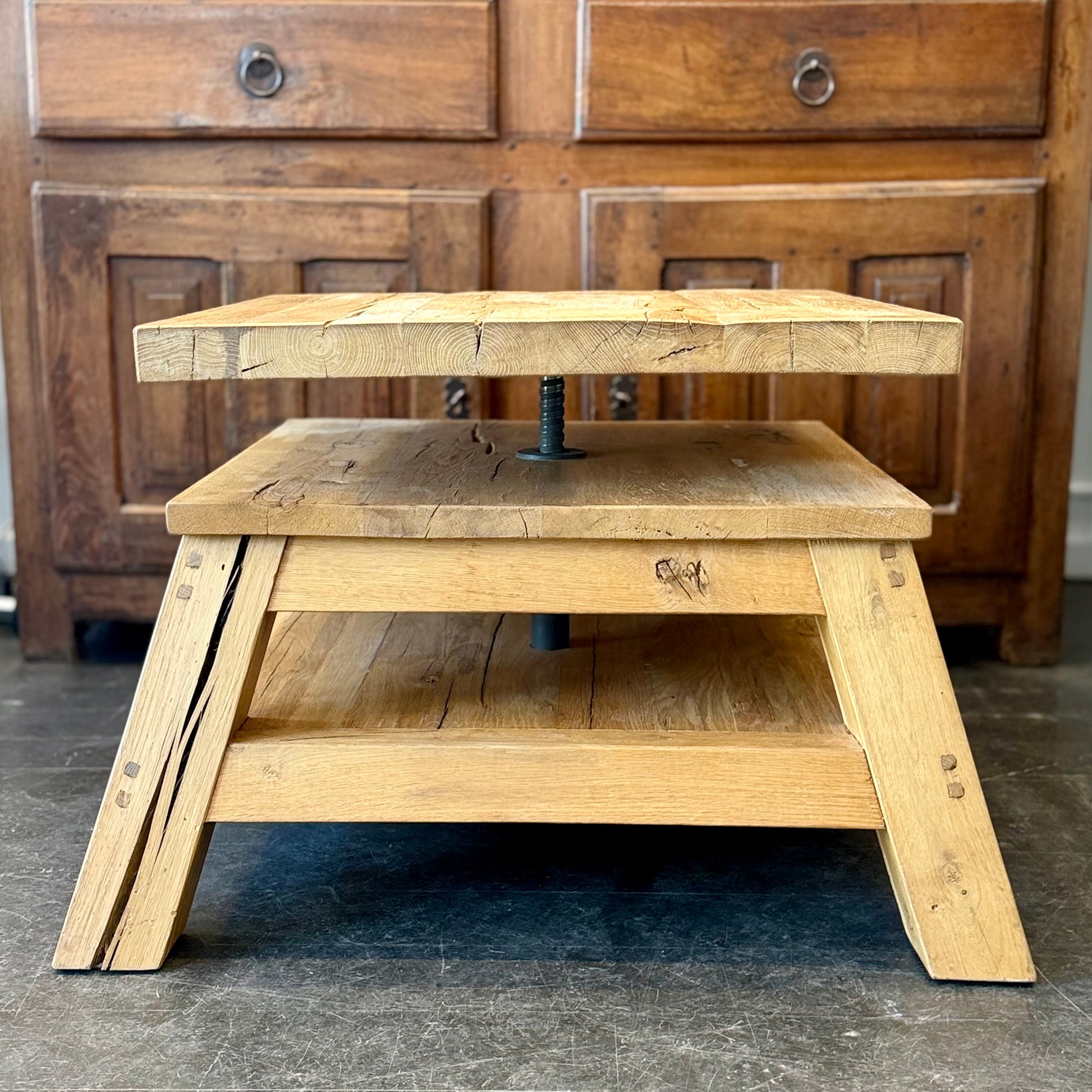 Wooden step stool with a metal handle in front of a wooden dresser.