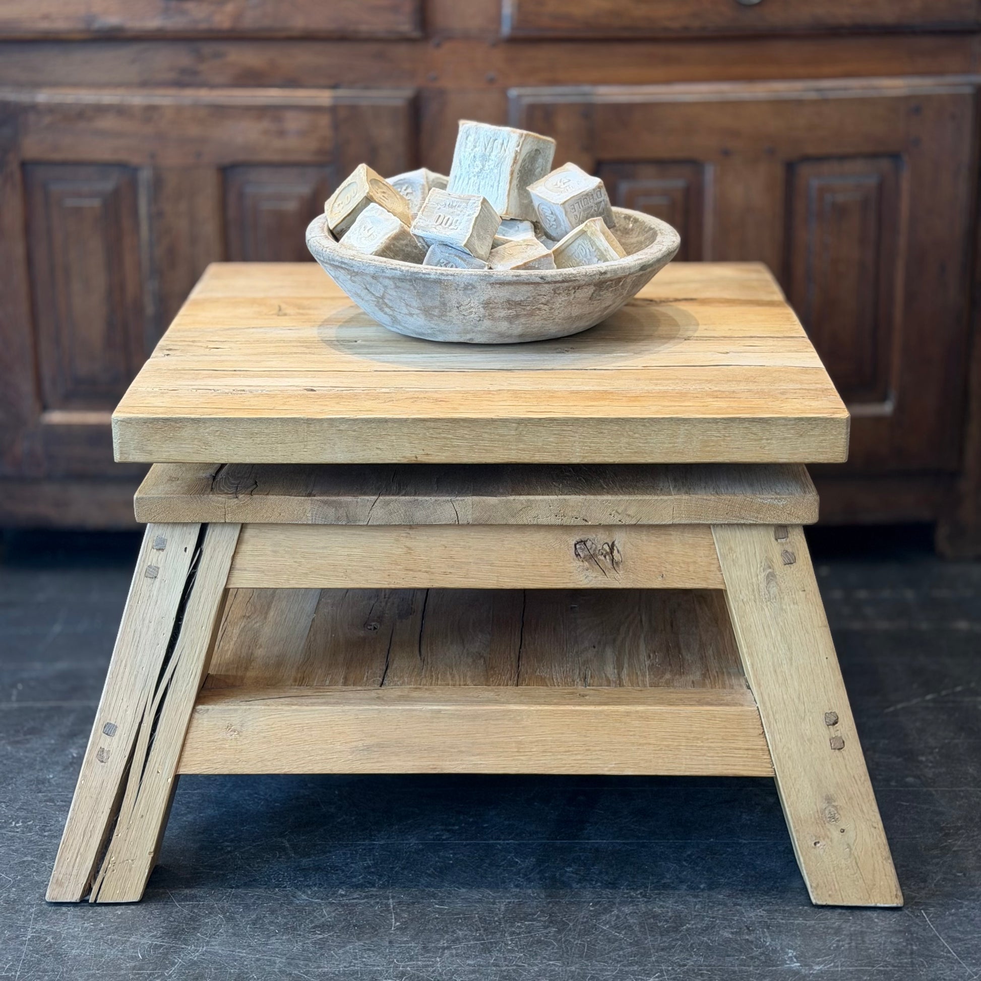 Wooden stool with a bowl of wooden blocks on a dark floor.
