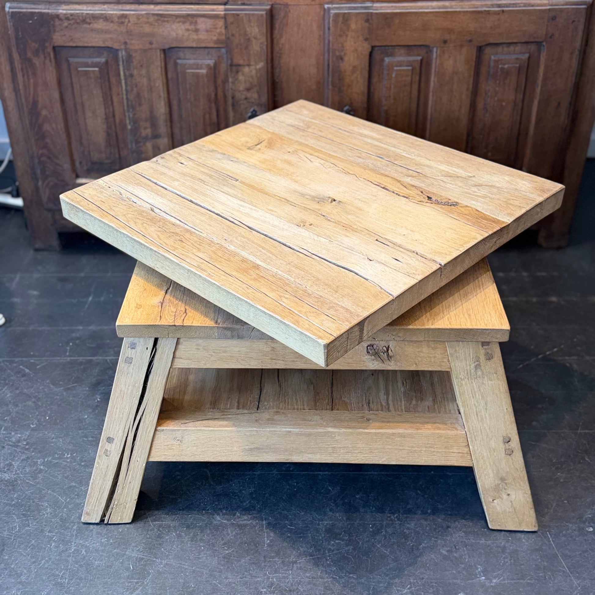 Wooden nesting tables on a dark floor with wooden paneling in the background