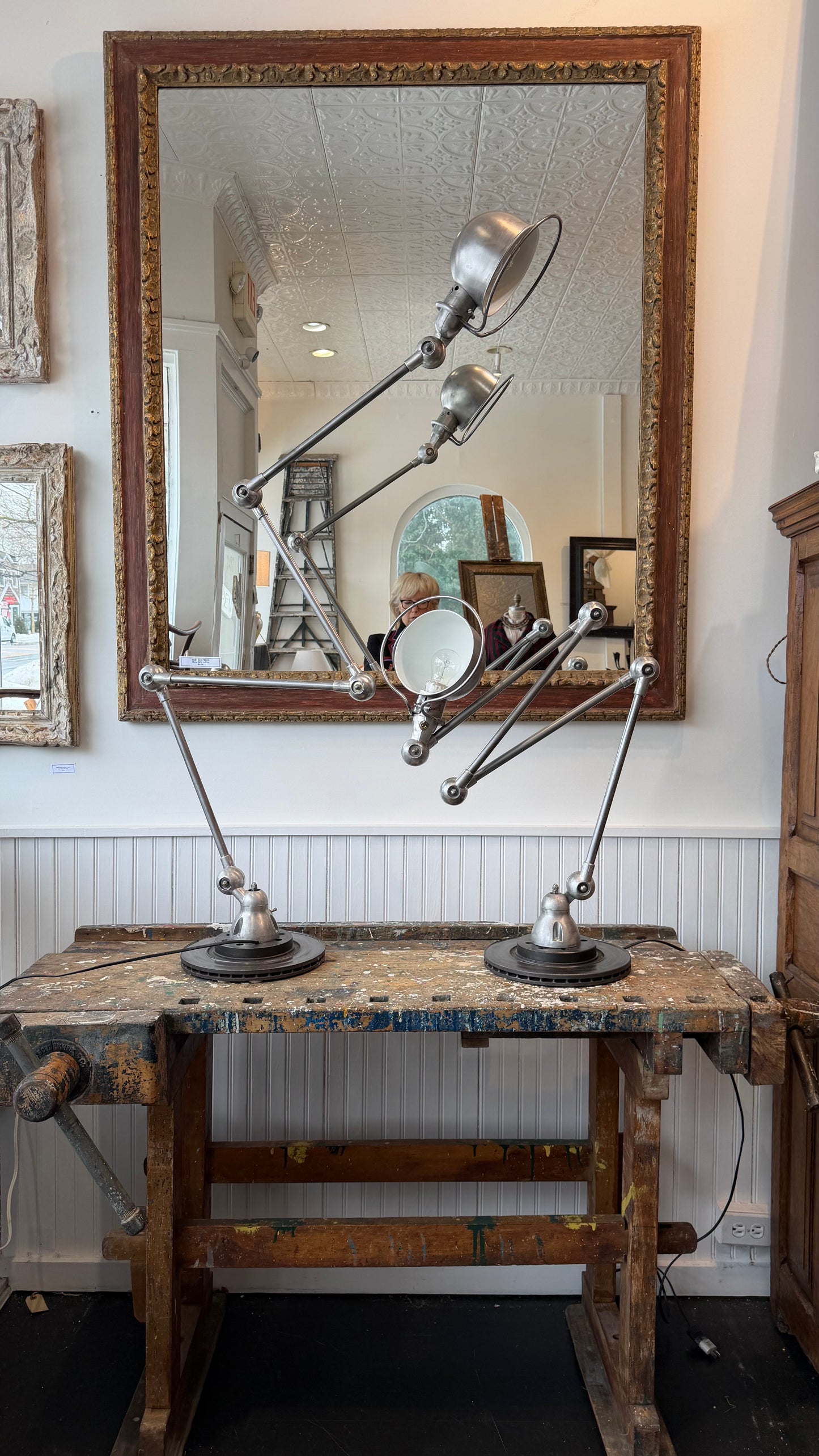 Vintage-style workbench with lamps and a large mirror on a white wall.